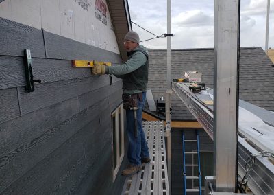 Photo of dean checking the level of the new siding.